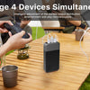 A portable power bank is shown charging four devices simultaneously on a wooden table outdoors.
