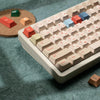 A close-up view of a white mechanical keyboard with retro colored PBT keycaps, including red, orange, and blue keys.