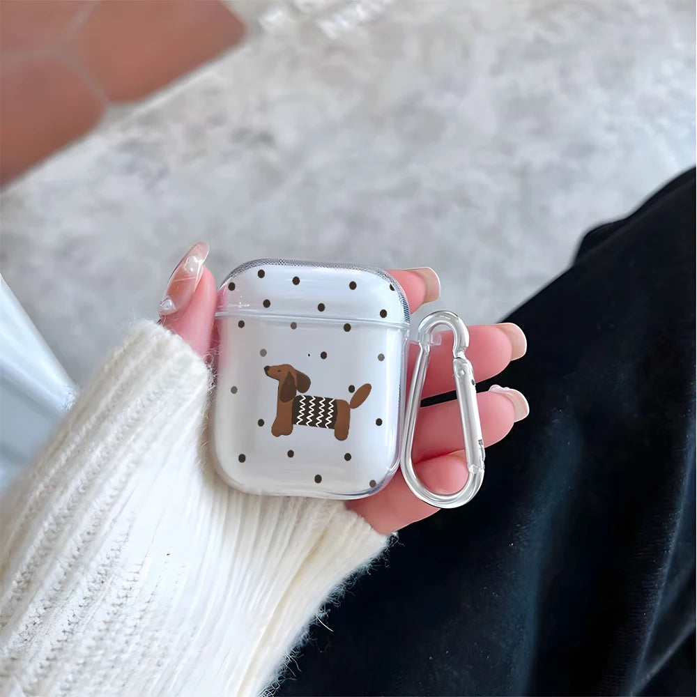 A hand holds a clear silicone case with a polka dot pattern and a dachshund design for AirPods.