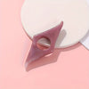 A translucent mauve resin thumb book stand with a cutout, resting on a pale pink surface.