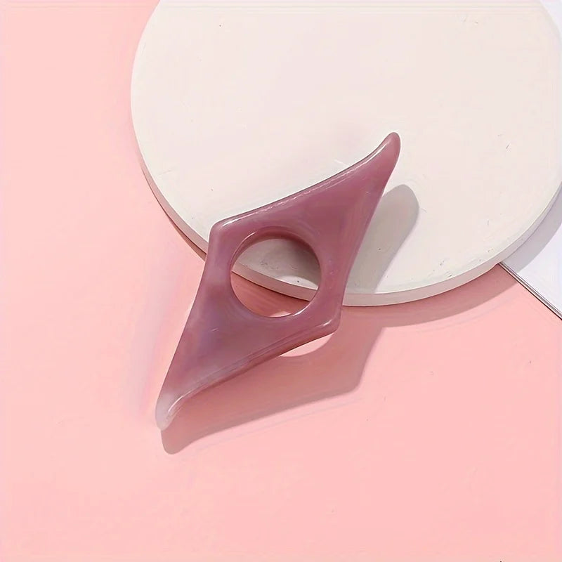 A translucent mauve resin thumb book stand with a cutout, resting on a pale pink surface.