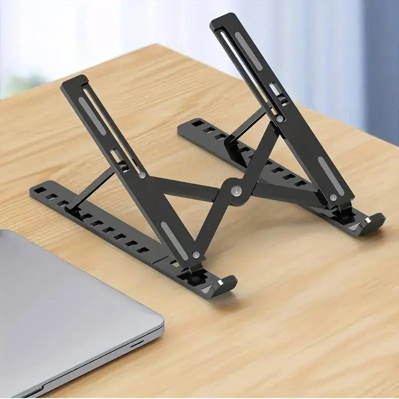 Black adjustable foldable laptop cooling stand resting on a wooden surface.