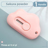 Rosa Sakura-Pulverwerkzeug mit Griff und runder Knopf vor hellblau-grauem Hintergrund