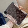 A hand holds a tablet in a leopard print leather case with a clear protective cover.