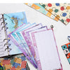 A stack of colorful A6 budget planner binders and sheets with decorative covers are displayed on a white surface.