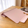 A pink magnetic protective case for an iPad Pro or iPad Air resting on a wooden table.