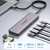 A silver 7-in-1 USB-C hub with multiple ports including HDMI, USB 3.0, and SD card readers is shown connected to a laptop.