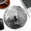 Silver disco ball shaped mouse pad with a non-slip rubber base next to a laptop and a coffee cup.