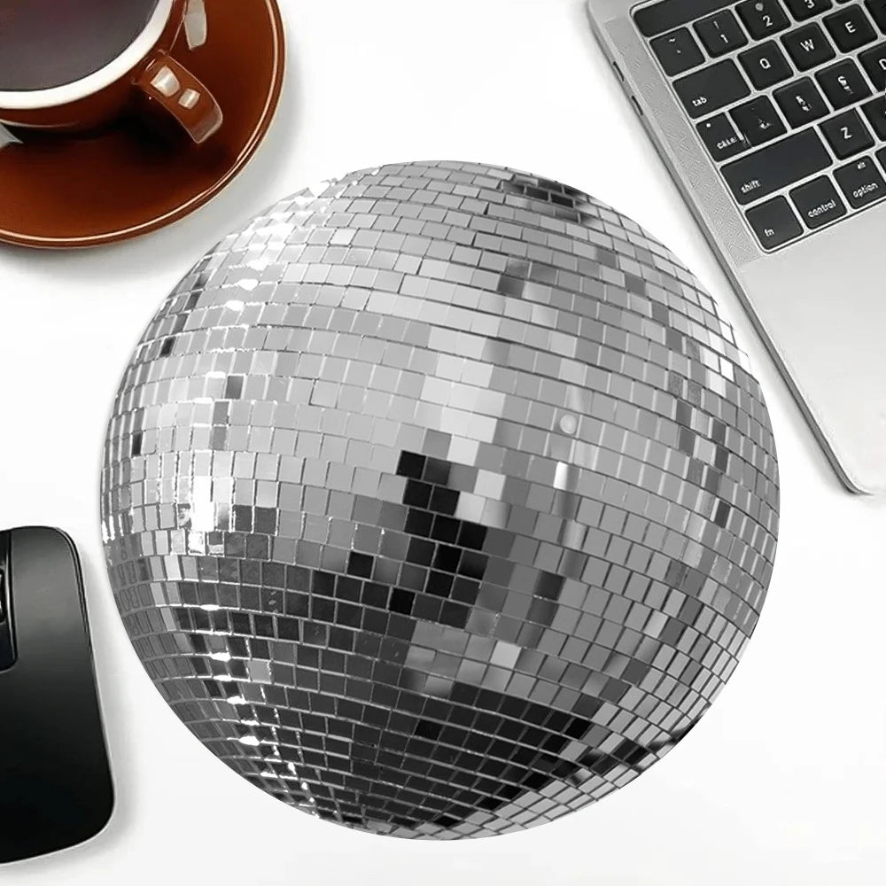 Silver disco ball shaped mouse pad with a non-slip rubber base next to a laptop and a coffee cup.