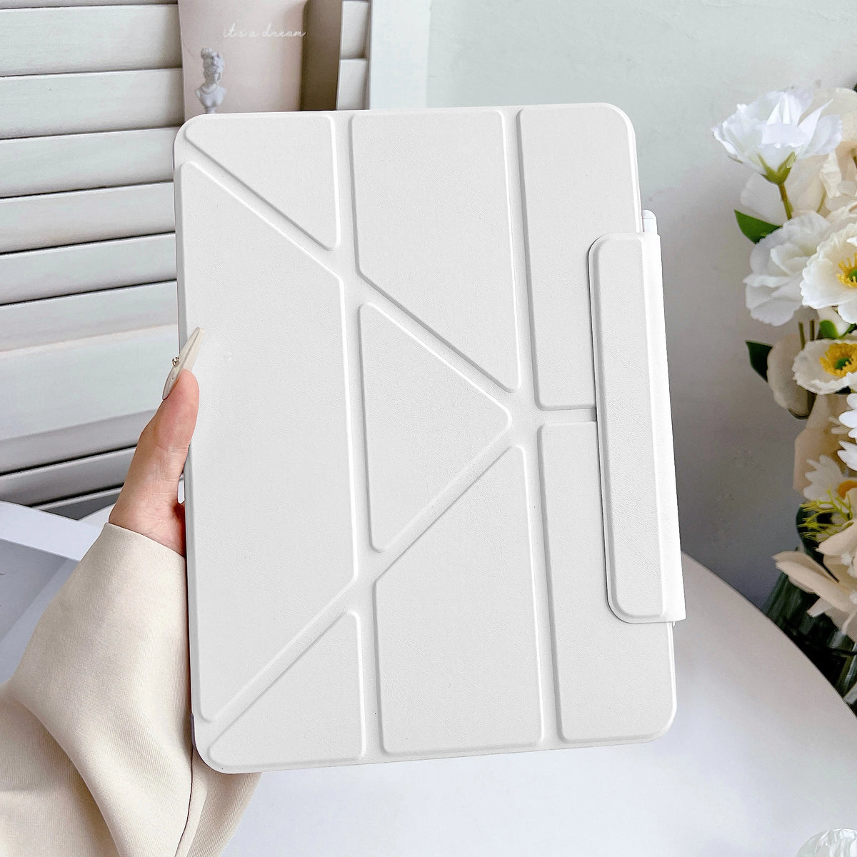 Una funda protectora de cuero sintético blanco premium para un iPad, sostenida por una mano.