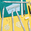 A collection of silver precision craft knives and blades laid out on a green cutting mat with various tools.