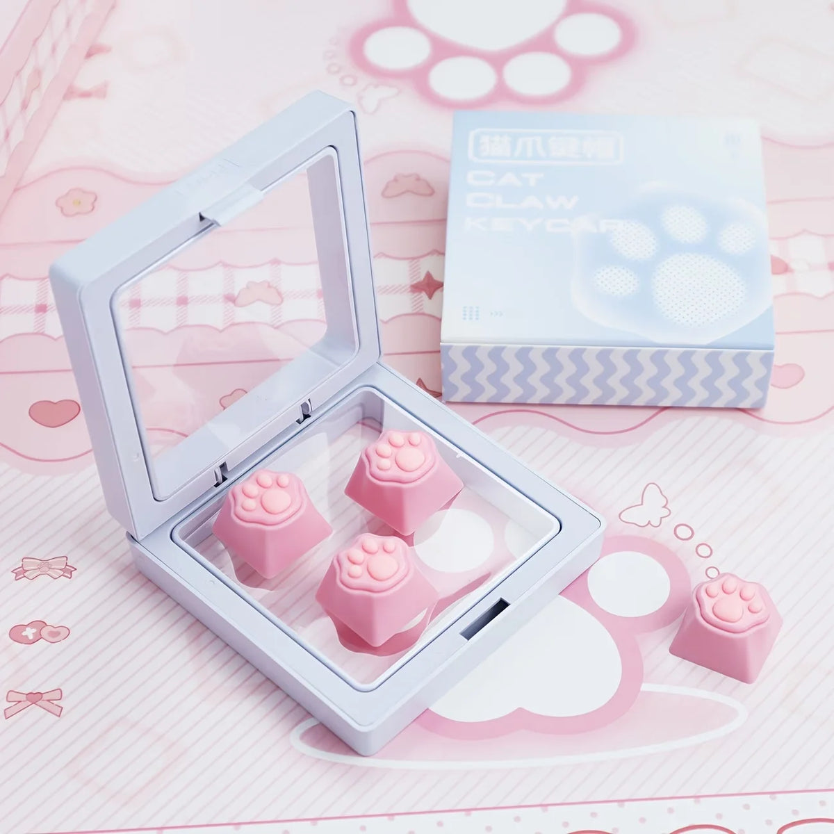 A clear plastic case holds pink cat paw and heart keycaps for MX switches on a pink background.