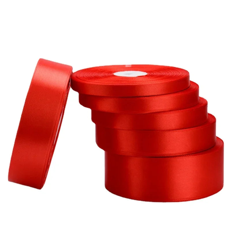 A roll of red satin ribbon with a white core and a separate ribbon strip shown on a white background.