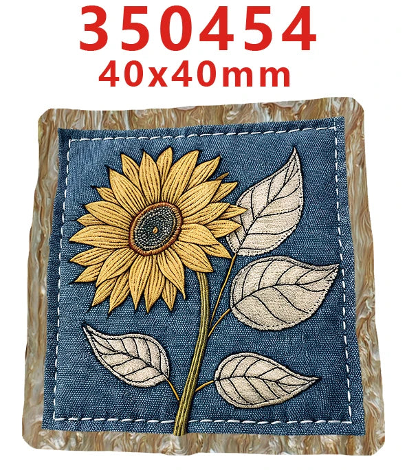 A fabric embroidery featuring a large yellow sunflower and several green leaves on a dark blue background.