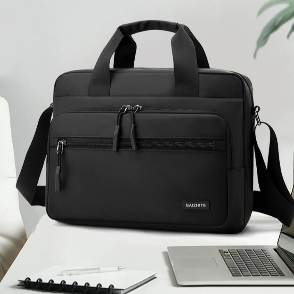 A black Oxford cloth crossbody briefcase with a laptop compartment and shoulder strap resting on a white surface.