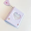 A purple photo card binder with a heart-shaped window and a charm attached, used for Kpop albums.