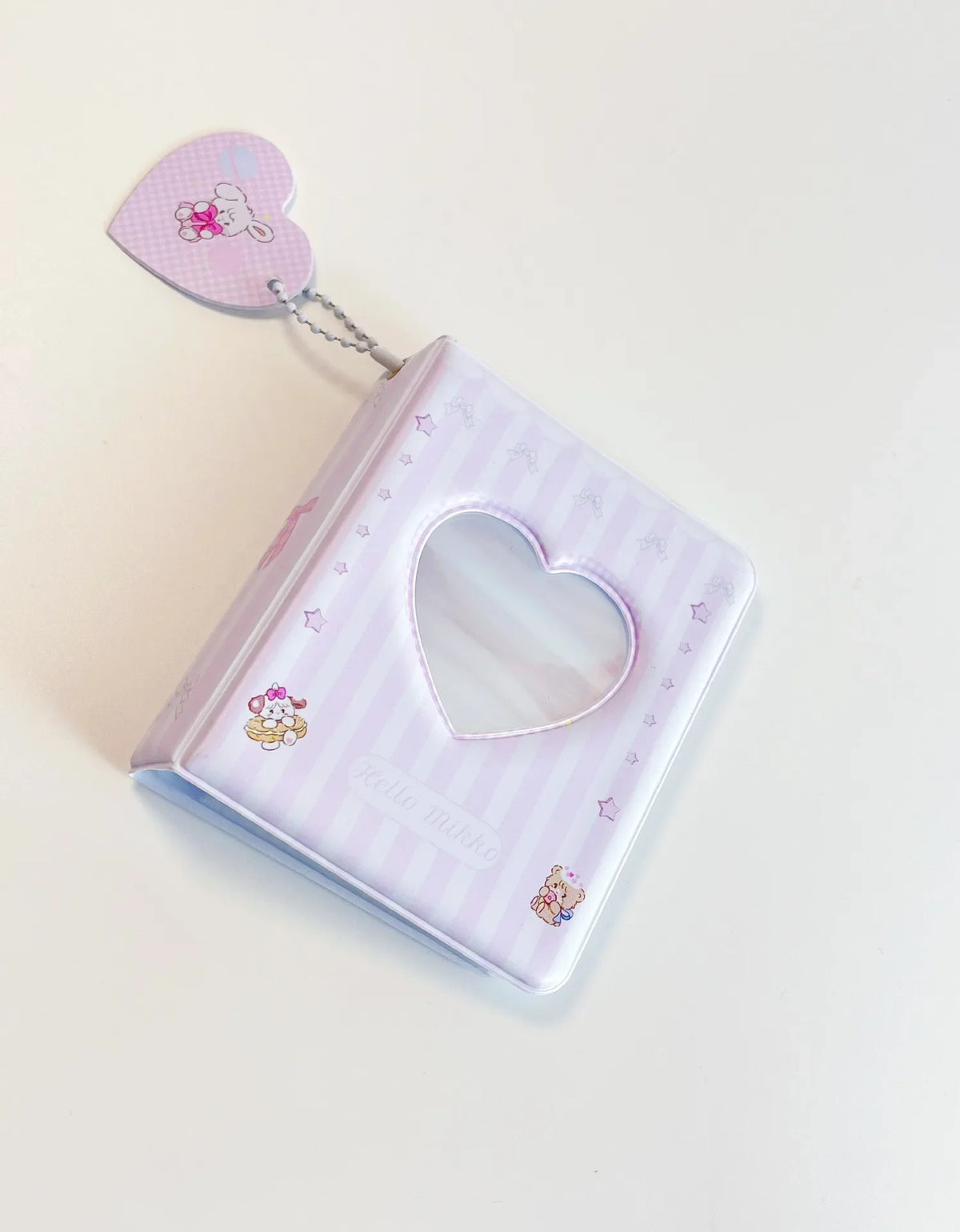 A purple photo card binder with a heart-shaped window and a charm attached, used for Kpop albums.