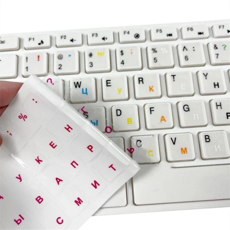 A close-up view of a white keyboard with transparent Russian language stickers placed on the keys.