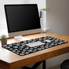 Black pet paw print desk mat placed on a wooden desk in an office setting.