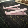 Pink ergonomic keyboard height adjuster stand with measurement lines on a dark surface.