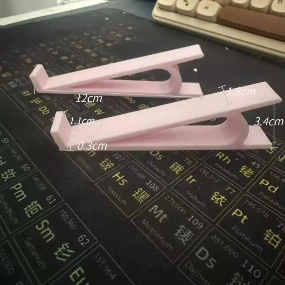 Pink ergonomic keyboard height adjuster stand with measurement lines on a dark surface.