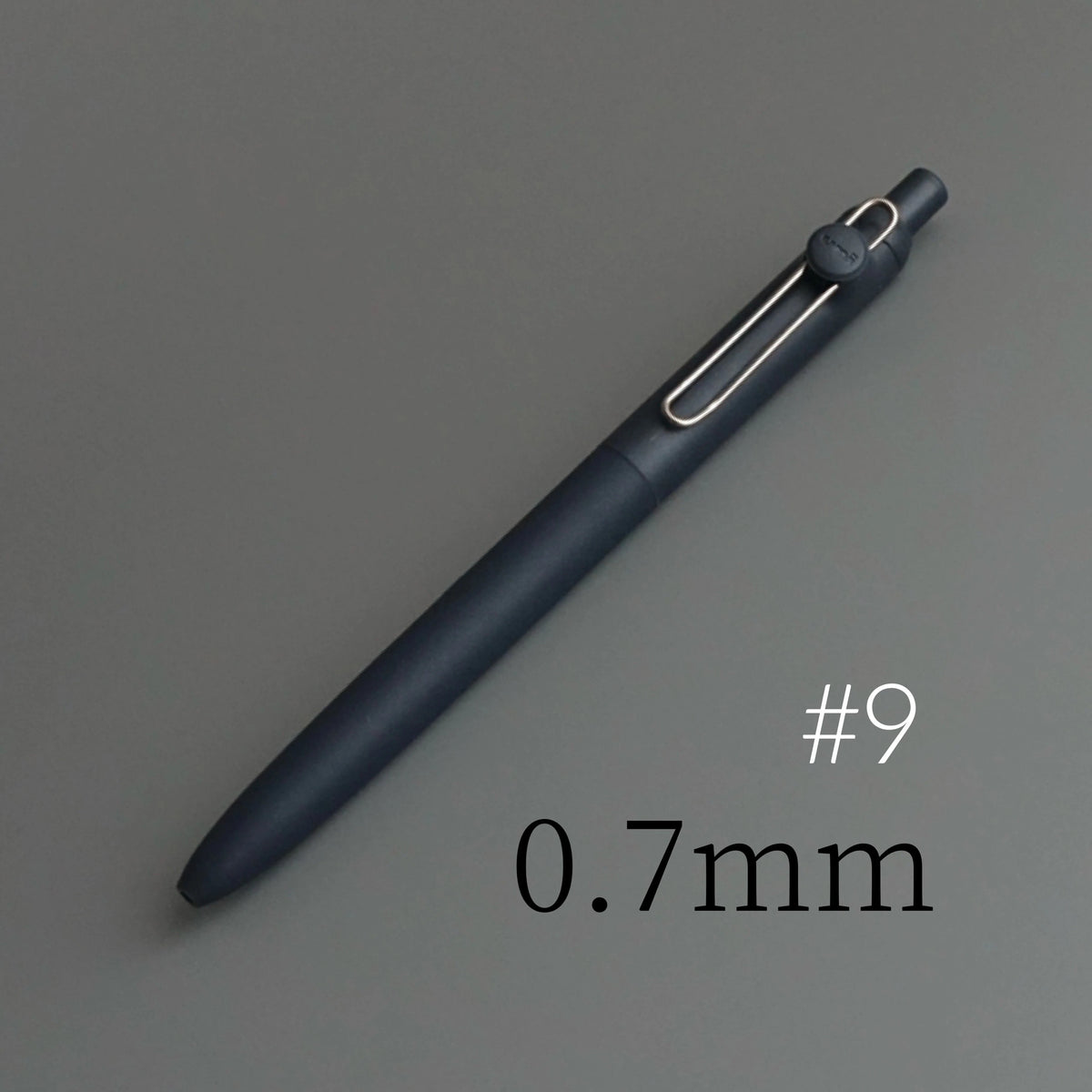 A dark blue precision gel pen with a silver tip is shown diagonally on a gray background, labeled #9 and 0.7mm.