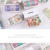 A collection of decorative transparent washi tape rolls in various colors and patterns displayed in cardboard boxes.