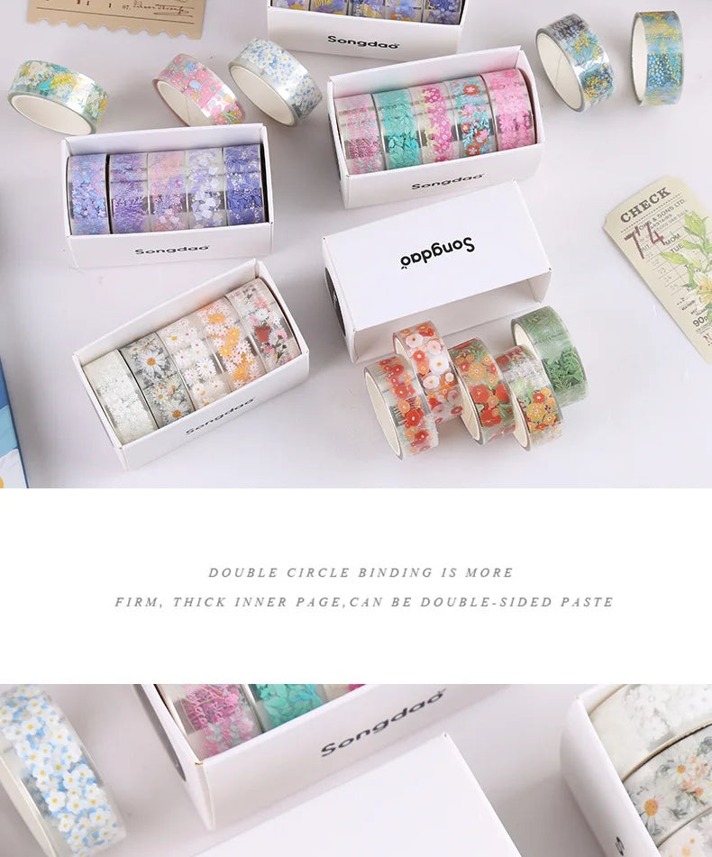 A collection of decorative transparent washi tape rolls in various colors and patterns displayed in cardboard boxes.