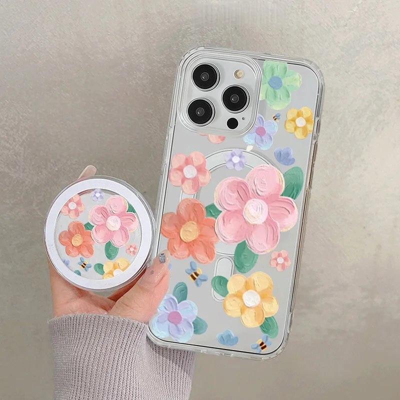 A hand holds a clear floral magnetic phone case for an iPhone featuring pink, purple, and yellow flowers.