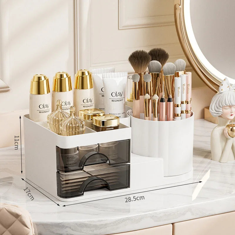 A white desk organizer with two clear storage drawers holds various makeup brushes and cosmetic products.