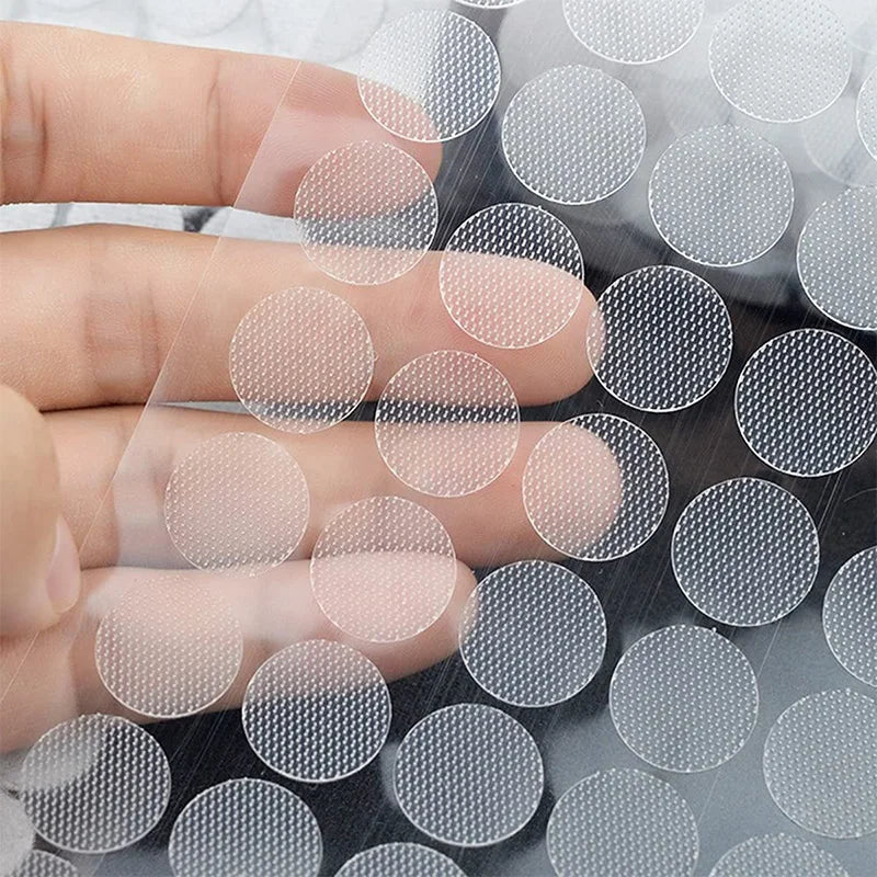 A hand is applying self-adhesive hook and loop fasteners onto a dark surface.