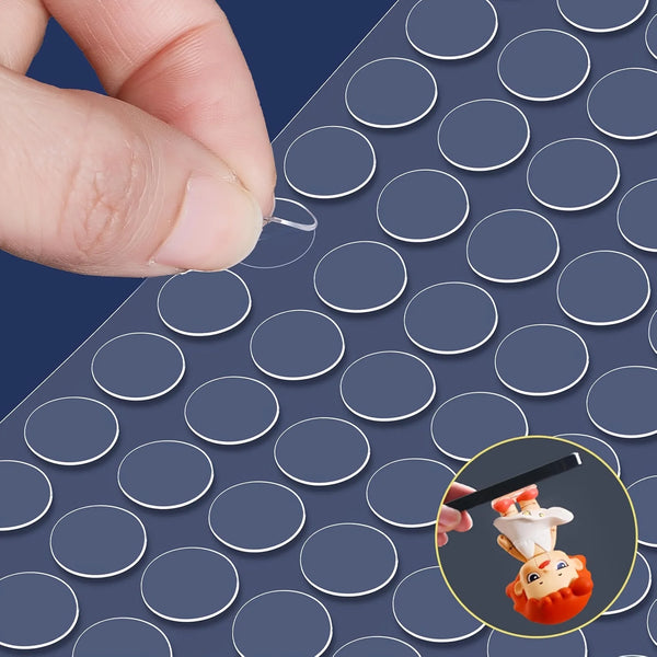 A hand places a removable double-sided adhesive dot onto a sheet of adhesive dots for crafts and decor.