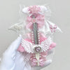 A hand holds an intricate angel wing art knife cutter featuring pink and white fabric details and pearl accents.