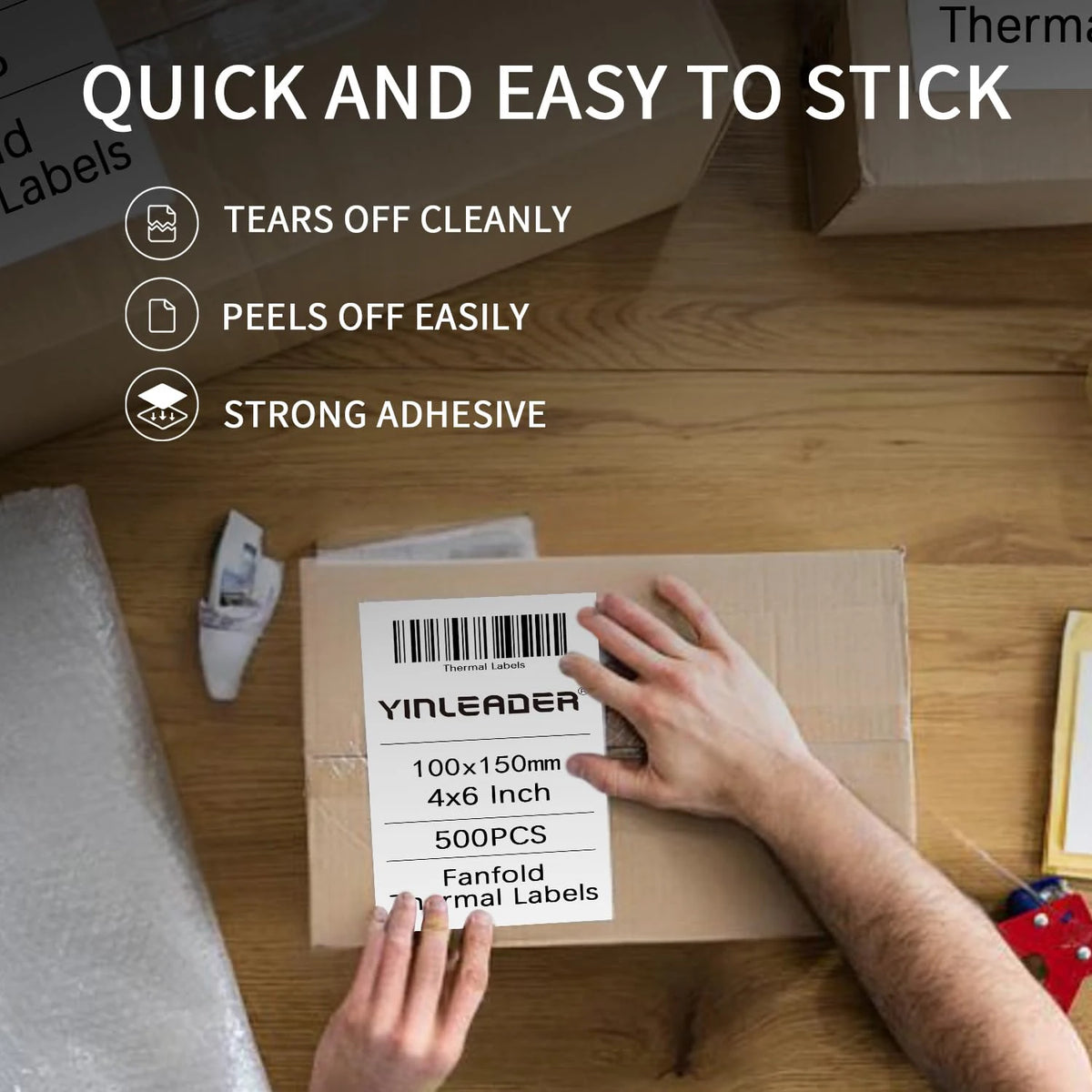 Hands are applying thermal shipping labels onto a cardboard box for printing.