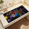 A black mouse pad featuring various cartoon characters and objects, displayed on a white desk.
