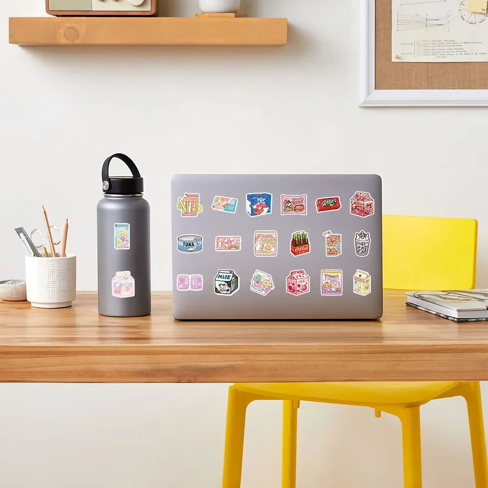 A laptop displaying a colorful cartoon sticker pack on a wooden desk next to a water bottle and pencil holder.