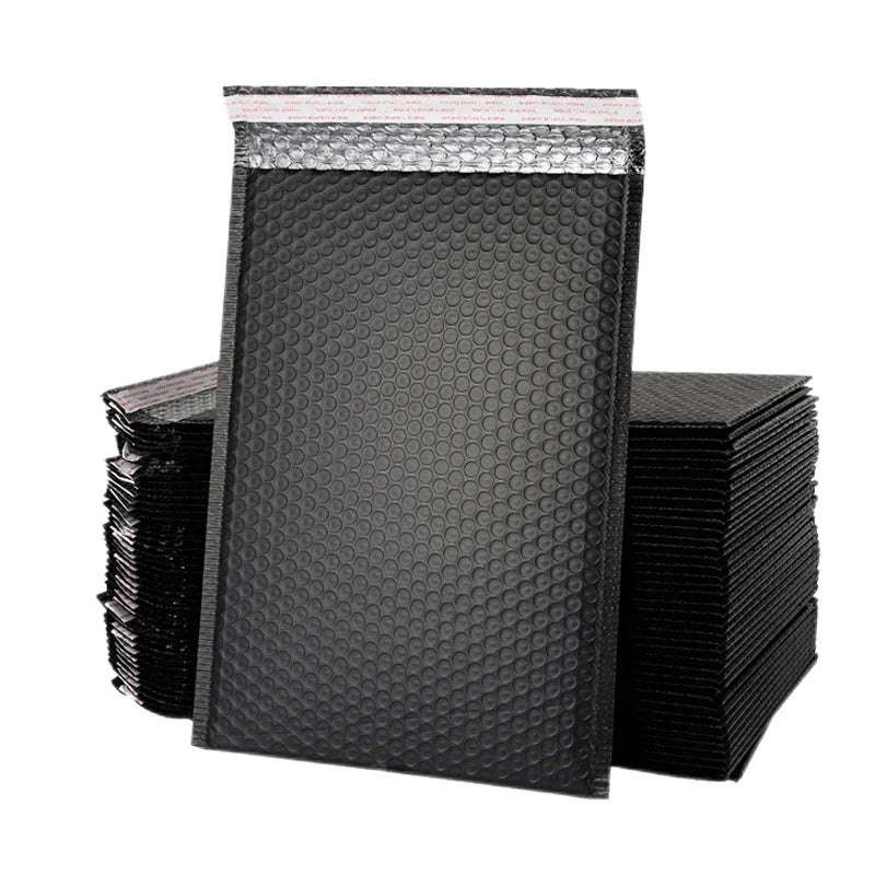 A stack of black self-sealing padded bubble mailers with pink edges.