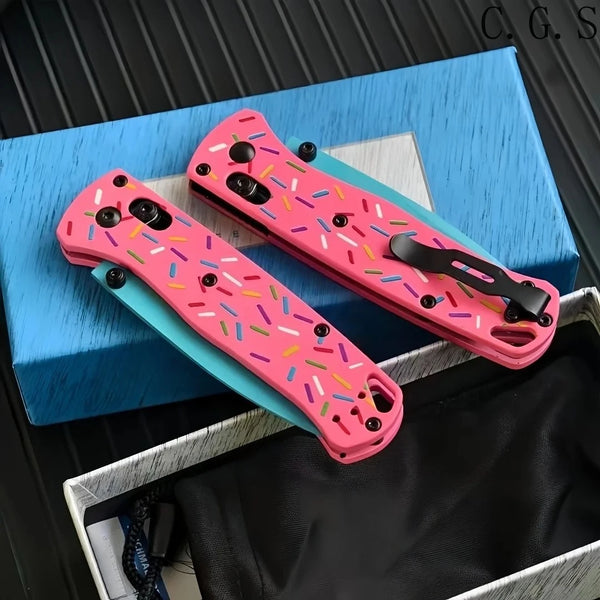 Pink donut acrylic folding knife with D2 steel blade displayed in a blue box.