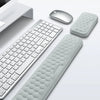 A light gray massage memory cotton wrist pad is shown next to a computer keyboard and mouse for finger pressure massage.