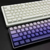Primer plano de un teclado mecánico con teclas de gradiente morado sobre una superficie oscura.