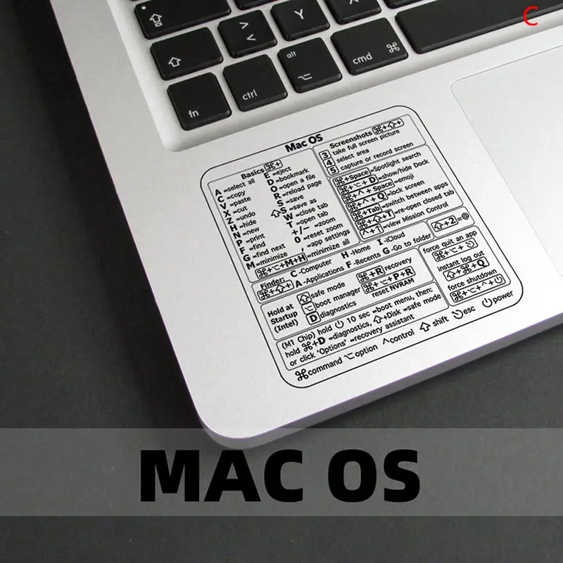 A close-up view of a laptop keyboard showing a Mac OS shortcut reference sticker.