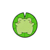 A green enamel pin shaped like a smiling frog