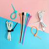 A collection of silicone cables with zipper closures in various colors, laid out on a pink and blue background.