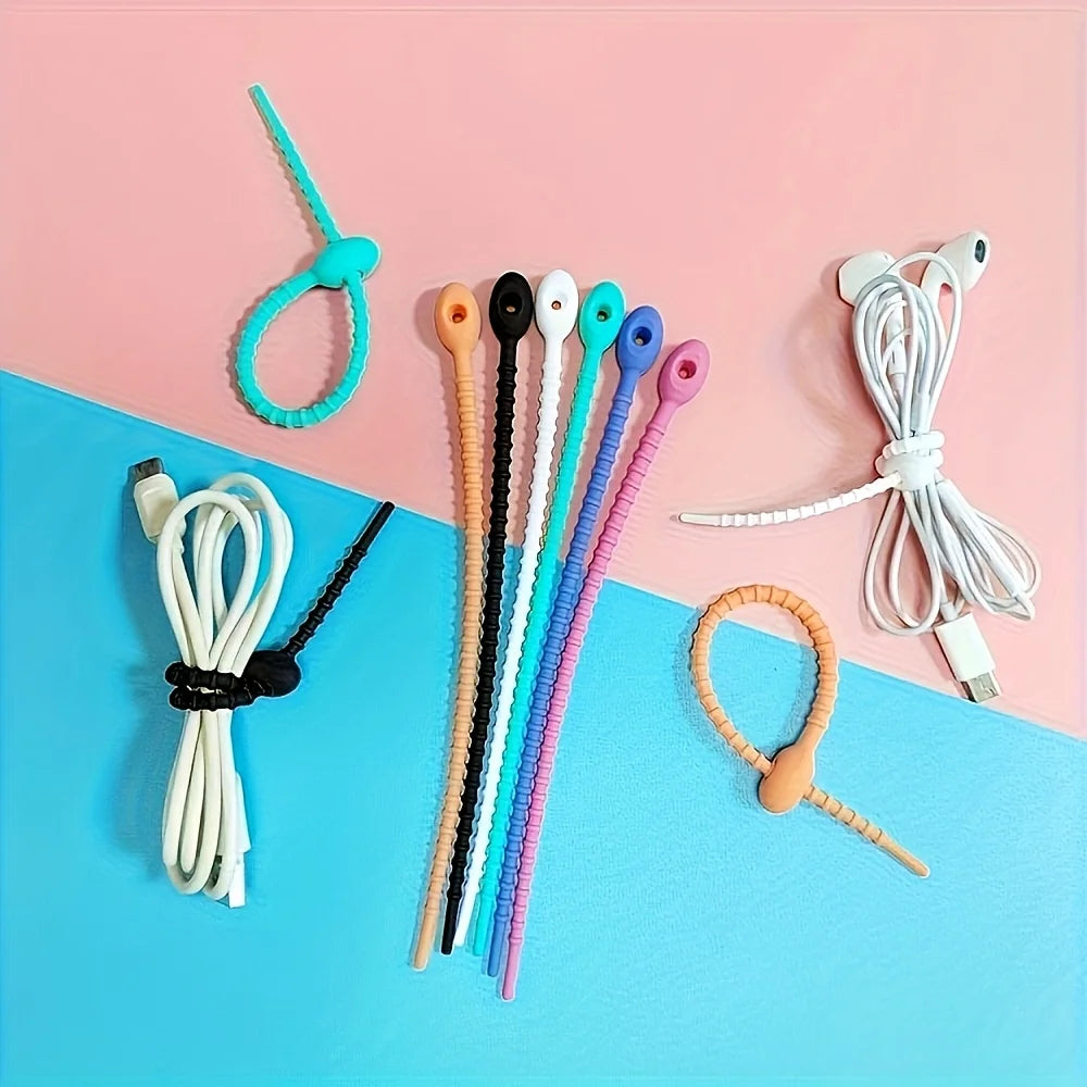 A collection of silicone cables with zipper closures in various colors, laid out on a pink and blue background.
