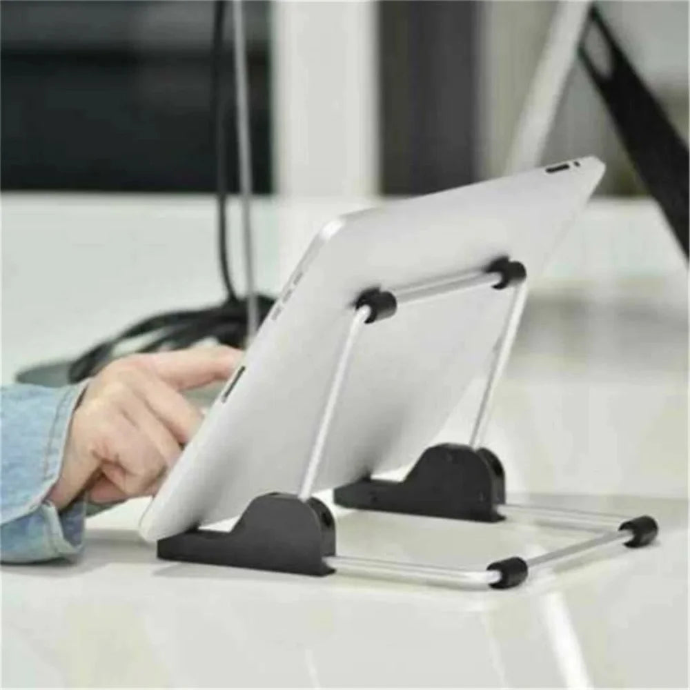 A white tablet is held in a foldable aluminum stand on a white desk surface.