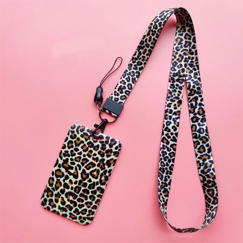 A leopard print ID holder lanyard keychain with a black strap and tag on a pink background.