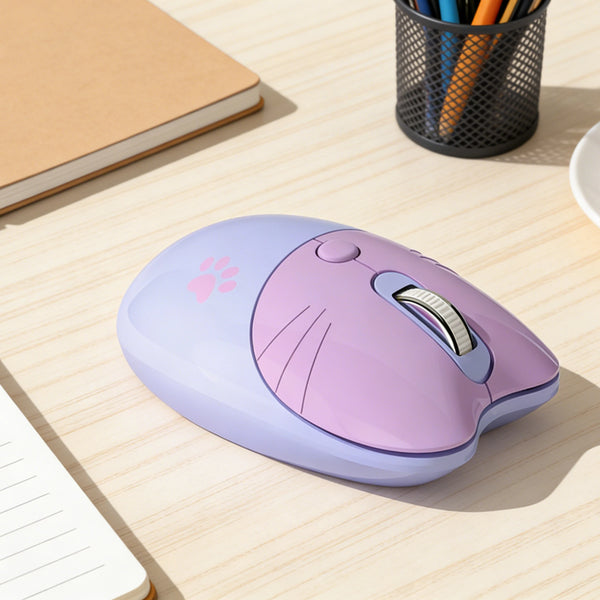 A purple cat-shaped wireless mouse with a pink accent is placed on a light wooden desk next to a notebook and pencils.