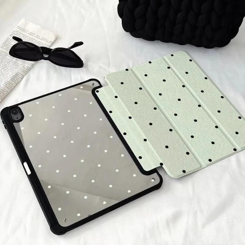 A black acrylic protective skin for an iPad case is shown next to a pair of sunglasses on a white surface.