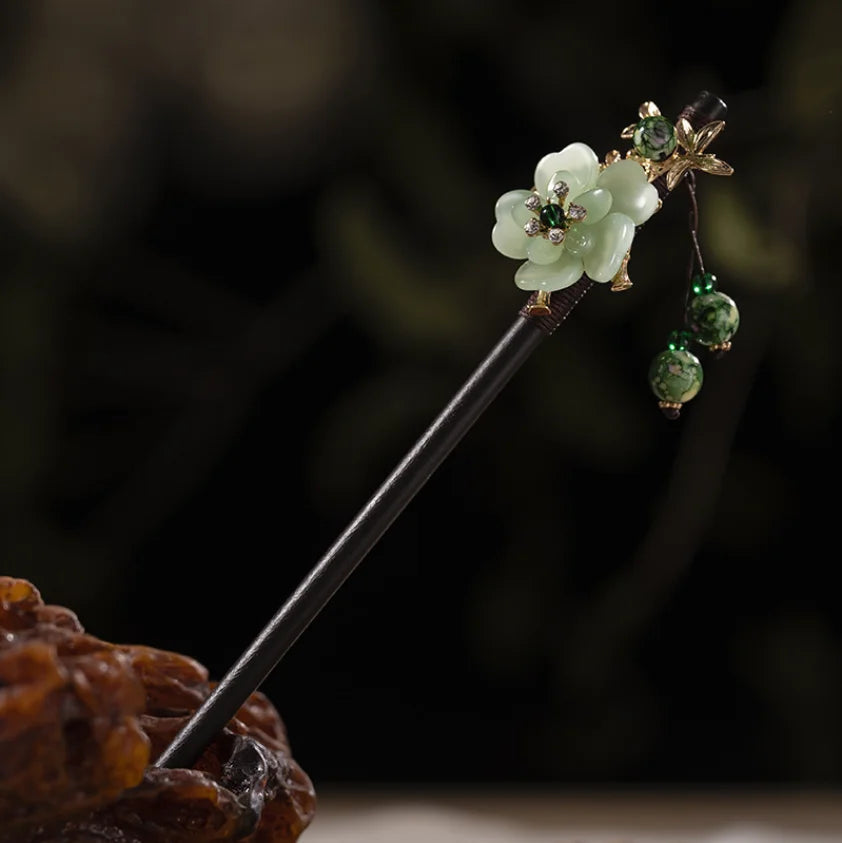 Un délicat accessoire de cheveux en bois floral avec une fleur vert pâle et de petites perles vertes sur un bâtonnet fin.