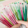A hand holds a set of multi-color Morandi gel pens in various shades of pink, green, and purple.